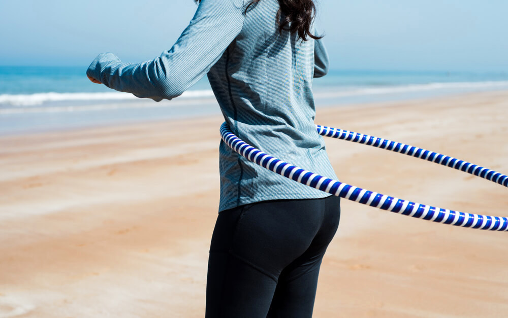 Unknown woman hoola-hooping at the beach