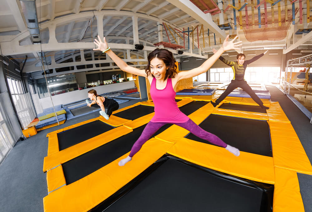 Happy excited woman jumping on large trampoline