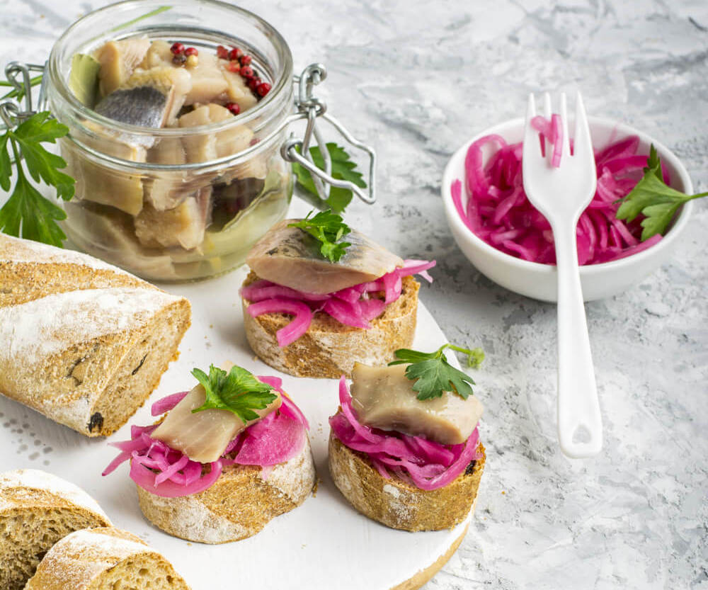 Small sliced herring and pink pickle on bread