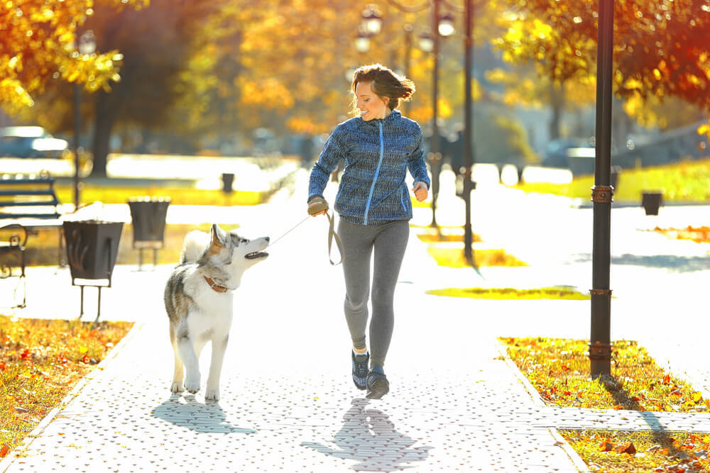 woman running outside with dog