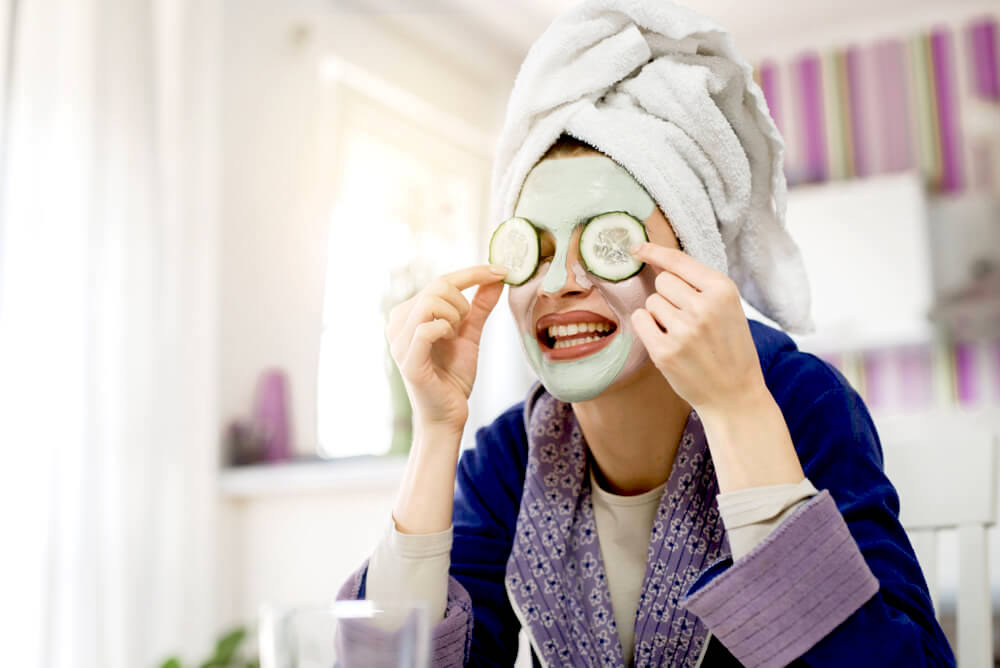 Applying face mask with cucumber slices