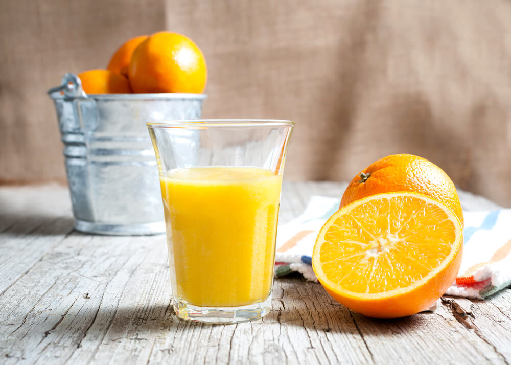 A glass of fresh orange juice, with halved orange