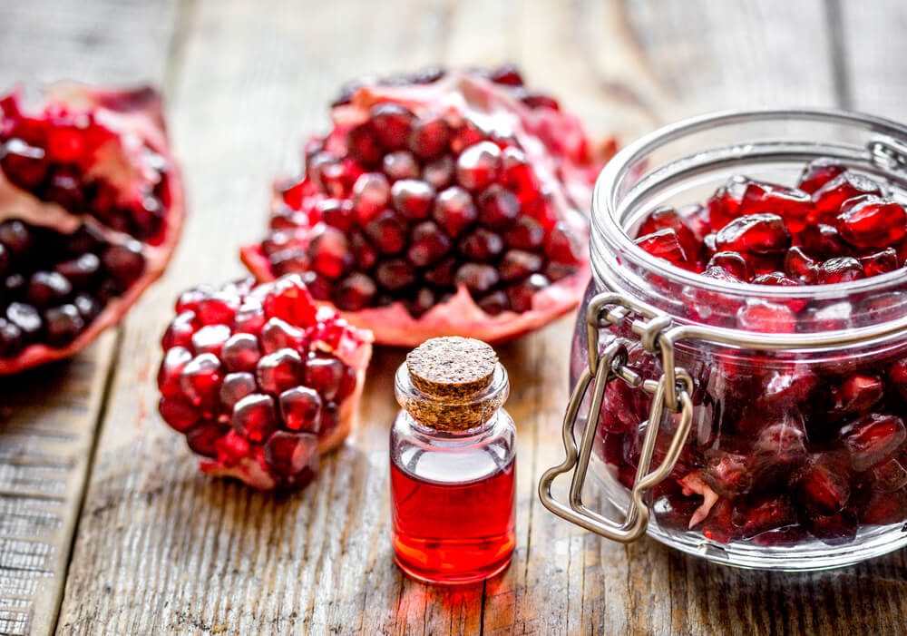 Loose pomegranate surrounding a small vial of pomegranate extract 