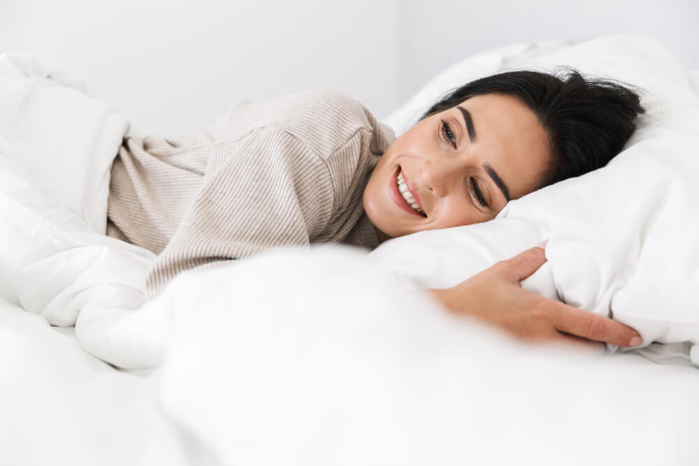 Happy woman smiling and sleeping in bed
