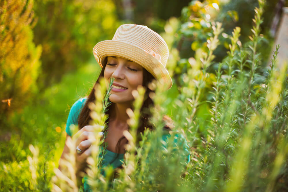 Woman enjoying the scent of rosemary in her garden