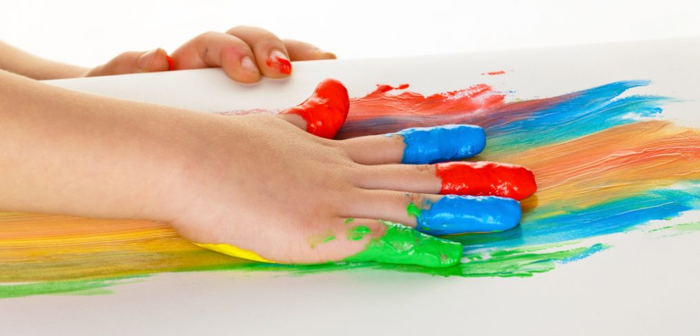 Child painting different colors on a sheet of paper.