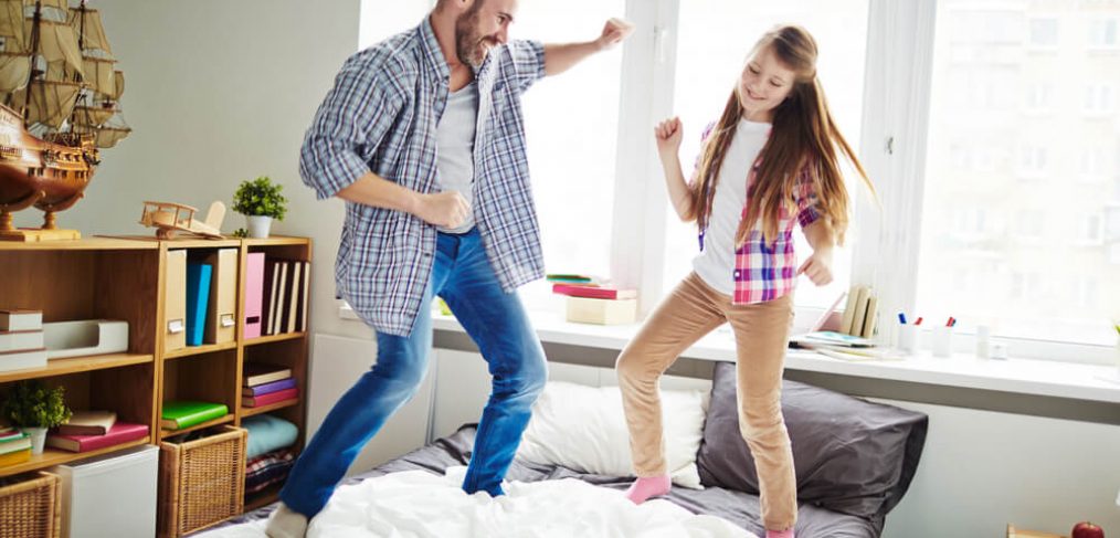 Father and daughter dancing on bed