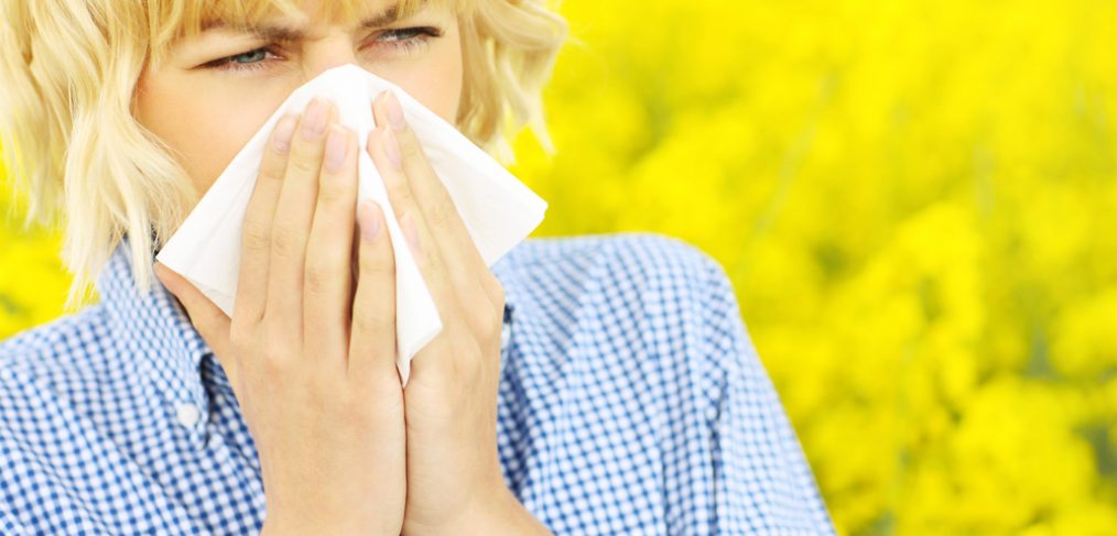 Woman sneezing into white napkin