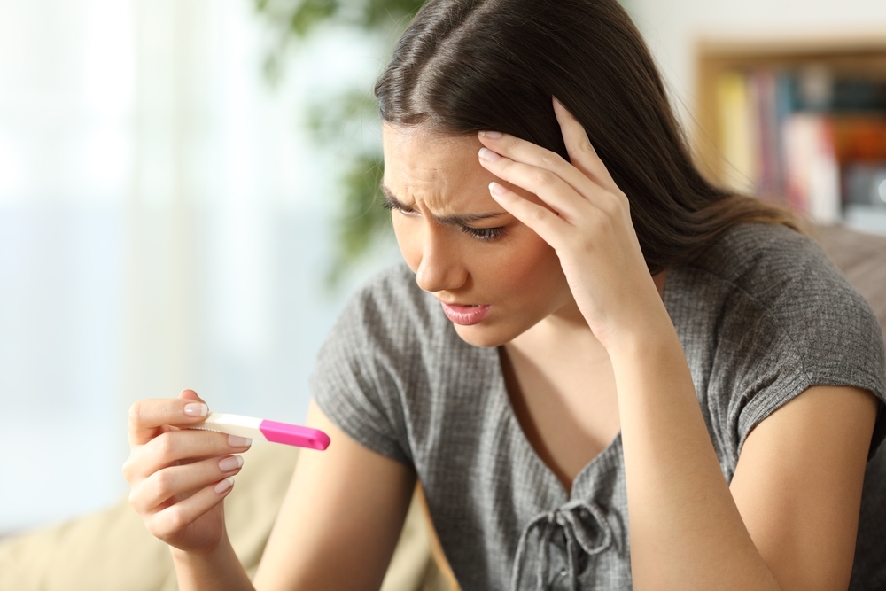 Women in distraught while looking at her pregnancy test.