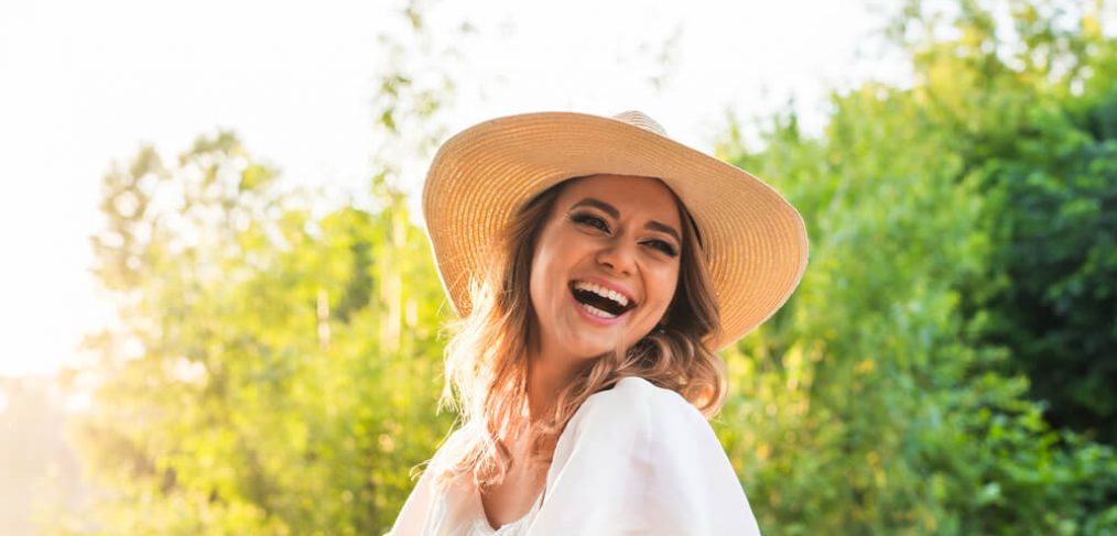 Woman with hat laughing outdoors
