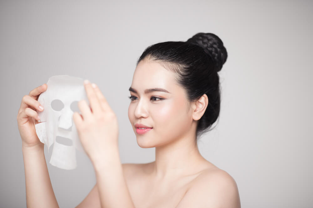 woman applying sheet mask