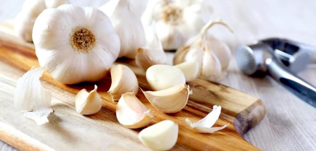 Whole garlic and garlic cloves on a wooden chopping board
